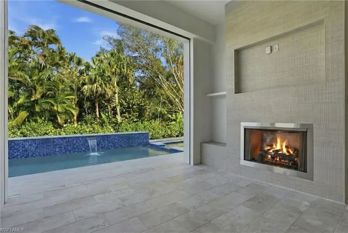 View of pool with a lit fireplace
