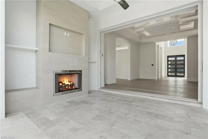 Unfurnished living room featuring a fireplace, arched walkways, and a high ceiling