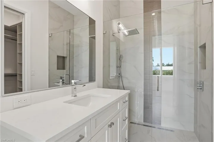 Bathroom featuring vanity, a marble finish shower, and a spacious closet