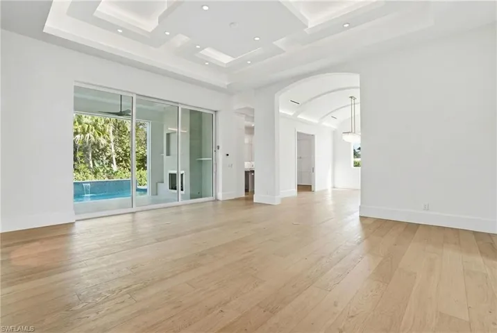 Spare room featuring arched walkways, light wood-style flooring, recessed lighting, and coffered ceiling