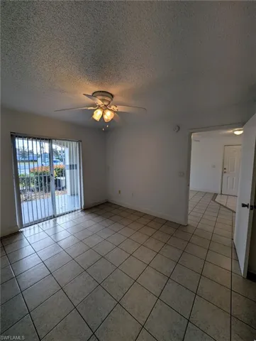 Spare room with light tile patterned floors, a ceiling fan, and a textured ceiling