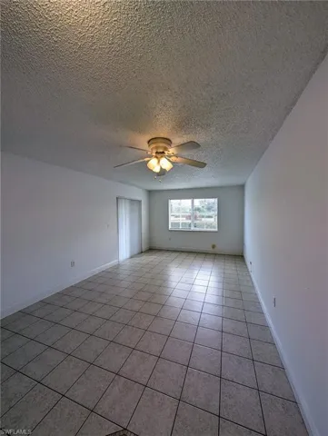 Spare room with a ceiling fan, light tile patterned floors, and a textured ceiling