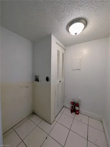Laundry room with a textured ceiling, hookup for a washing machine, and light tile patterned flooring