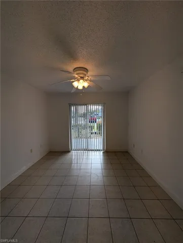 Unfurnished room featuring a textured ceiling, light tile patterned floors, and a ceiling fan