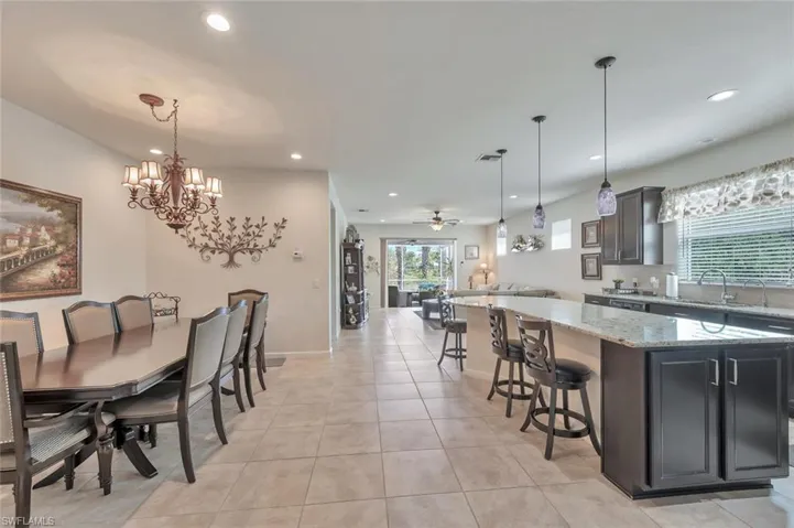 Kitchen with a kitchen breakfast bar, a center island, open floor plan, ceiling fan, and light stone countertops