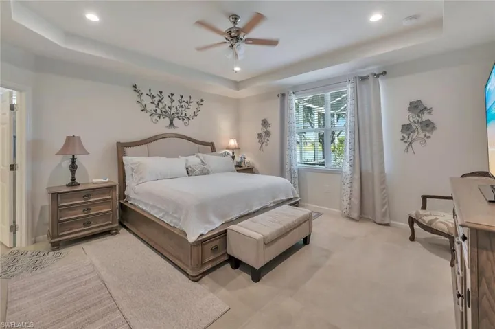 Carpeted bedroom featuring a tray ceiling, ceiling fan, and recessed lighting