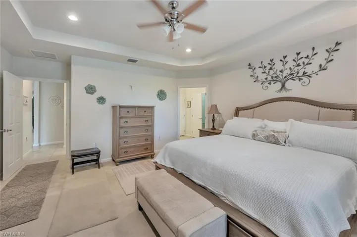 Bedroom with a tray ceiling, a ceiling fan, and recessed lighting