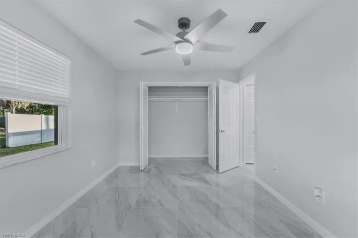Unfurnished bedroom with a closet, light marble finish flooring, and a ceiling fan