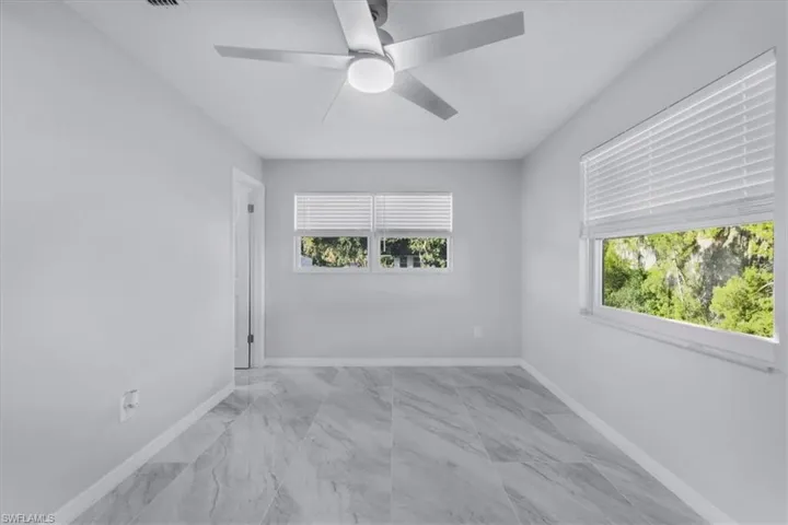 Spare room with ceiling fan and light marble finish flooring
