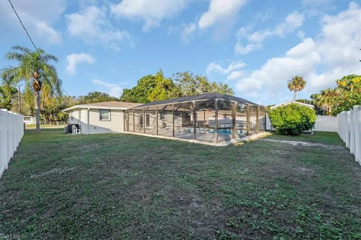 Rear view of property with a fenced backyard, a lanai, and a sunroom