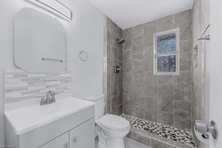 Full bath with a shower stall, vanity, and tasteful backsplash