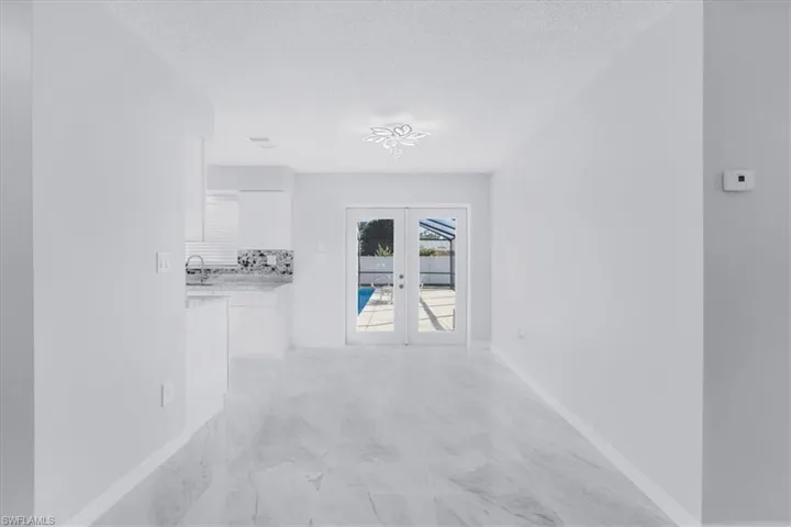 Hallway featuring french doors, a textured ceiling, and light marble finish floors