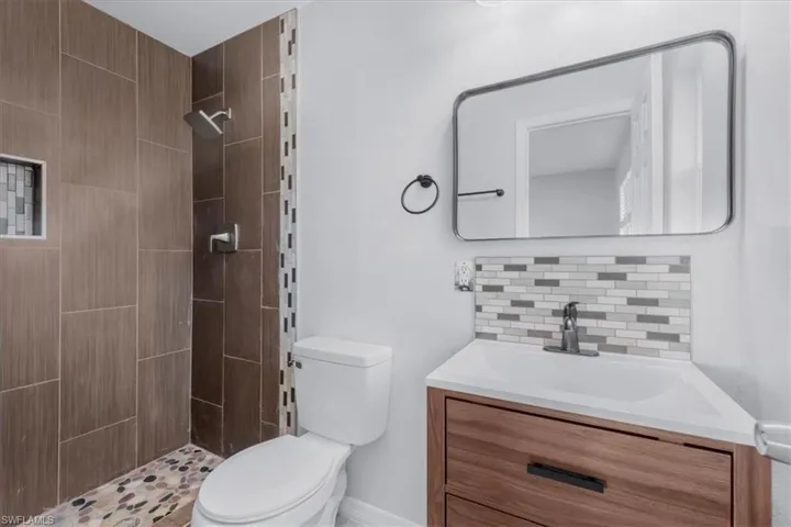 Full bathroom featuring vanity, decorative backsplash, and a tile shower