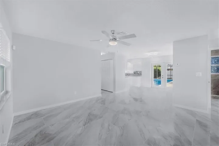 Unfurnished living room with ceiling fan and light marble finish flooring