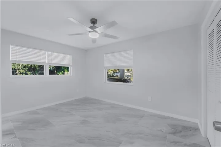 Spare room featuring light marble finish floors and ceiling fan