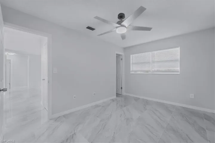 Empty room with light marble finish floors and a ceiling fan