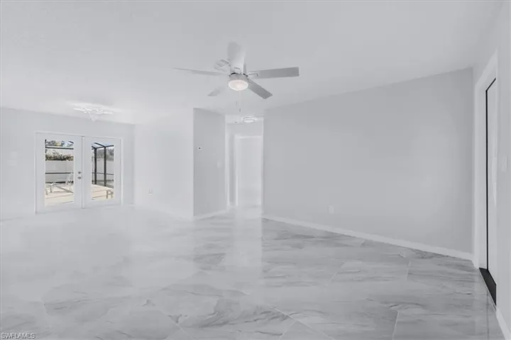 Empty room with french doors, light marble finish flooring, and a ceiling fan