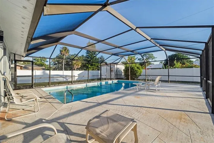 View of pool featuring a sunroom, a fenced backyard, a patio, and glass enclosure