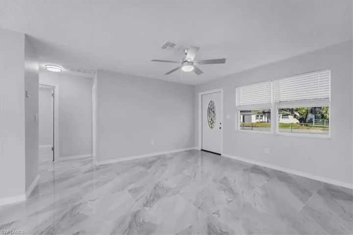 Foyer entrance with a textured ceiling, light marble finish floors, and ceiling fan