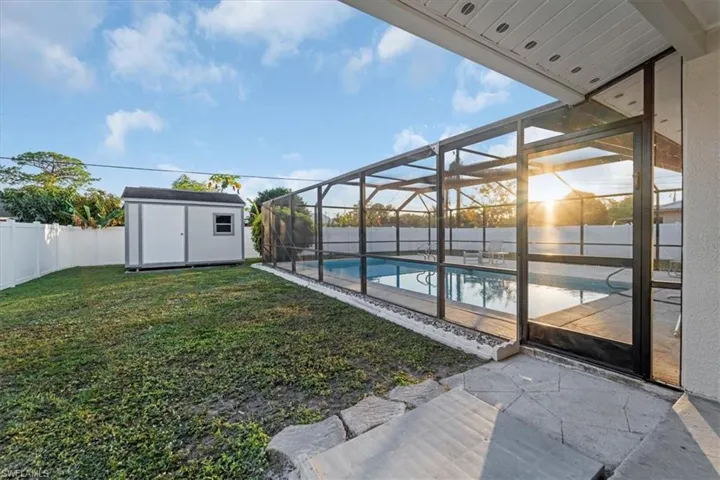 Fenced backyard with a sunroom, a lanai, a storage unit, and a patio area