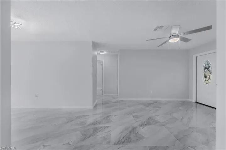 Empty room featuring a textured ceiling, light marble finish flooring, and ceiling fan