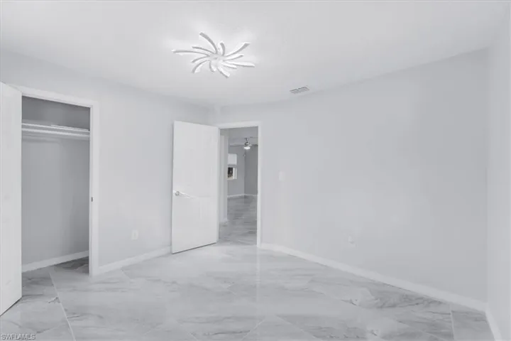 Unfurnished bedroom with light marble finish floors and a closet