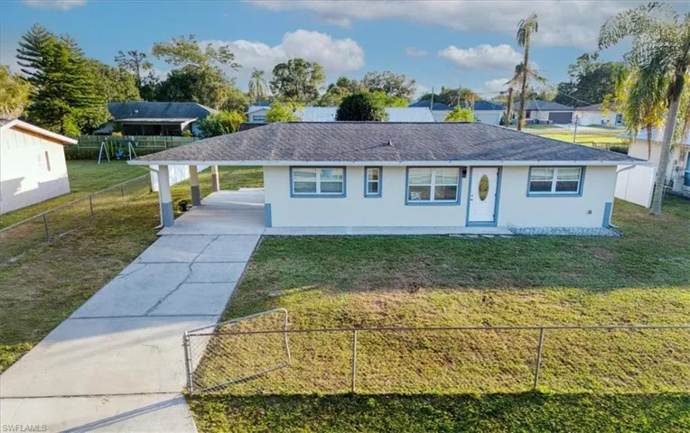 View of front of house with a fenced front yard, an attached carport, stucco siding, concrete driveway, and a shingled roof
