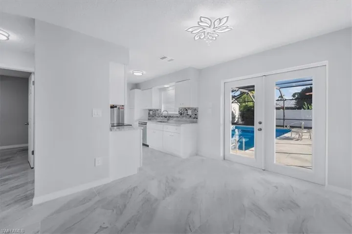 Unfurnished living room with a textured ceiling, french doors, and light marble finish floors