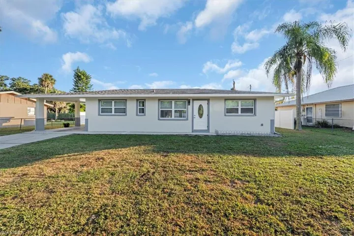Ranch-style house featuring an attached carport, driveway, and stucco siding