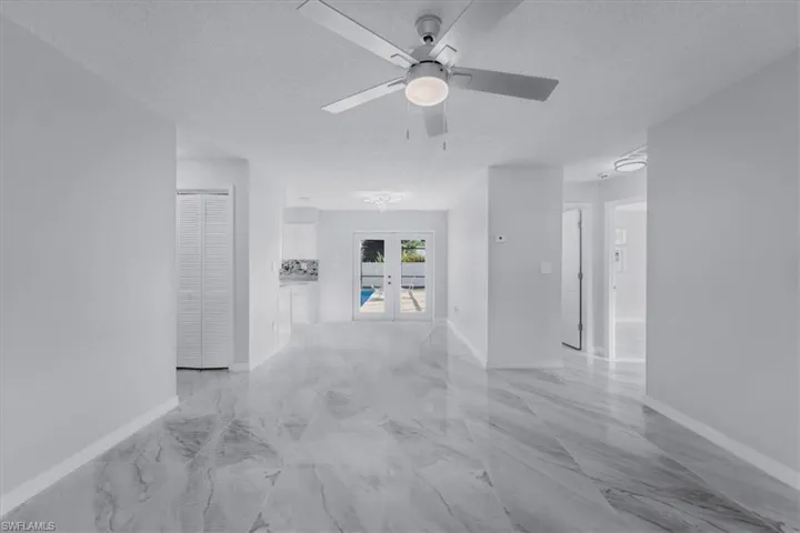 Hallway featuring french doors, a textured ceiling, and light marble finish floors