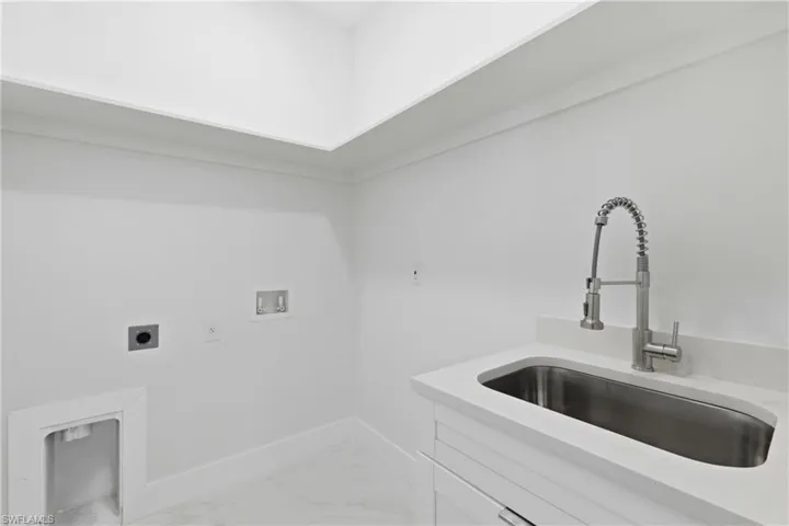 Laundry area with electric dryer hookup, washer hookup, cabinet space, and light marble finish flooring