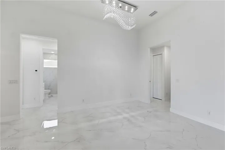 Unfurnished room featuring hanging lights and light marble finish floors
