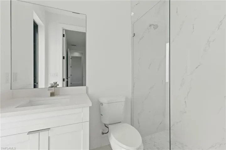Full bath featuring a marble finish shower and vanity