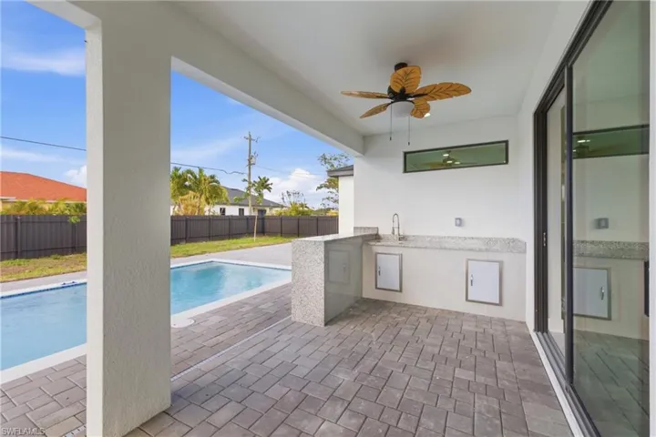 View of swimming pool featuring exterior kitchen, patio surround, and a fenced backyard