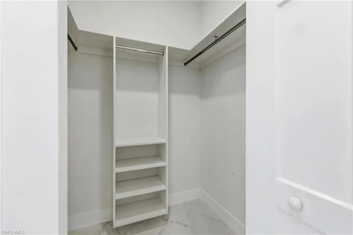 Walk in closet with light marble finish flooring