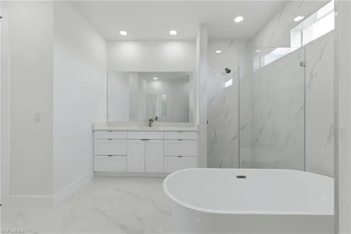 Bathroom featuring a marble finish shower, recessed lighting, vanity, light marble finish flooring, and a soaking tub