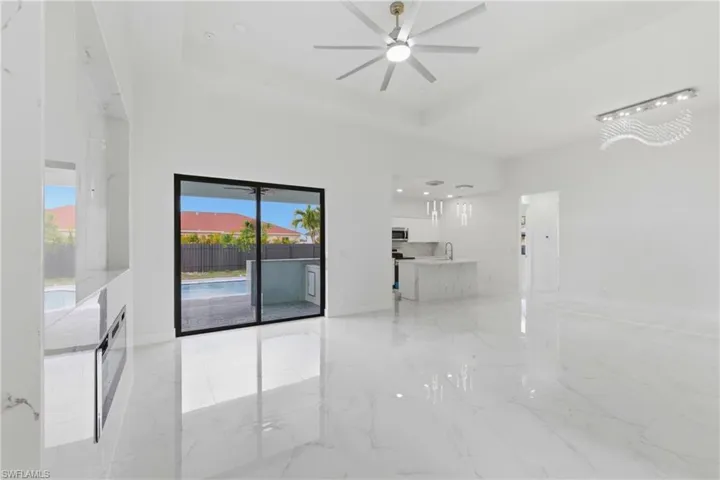 Unfurnished room featuring light marble finish flooring, a ceiling fan, a tray ceiling, and recessed lighting