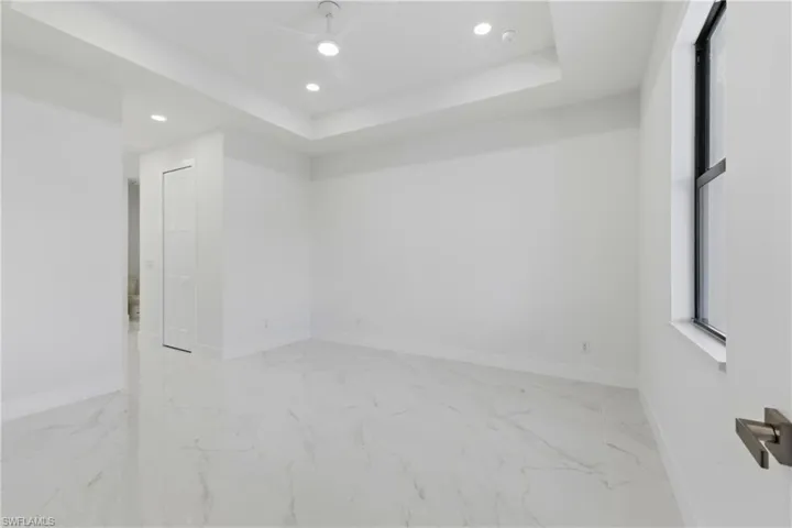 Unfurnished room with recessed lighting, ceiling fan, light marble finish floors, and a raised ceiling