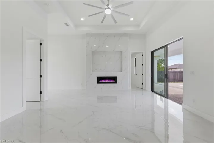 Unfurnished living room with light marble finish flooring, a premium fireplace, a ceiling fan, and recessed lighting