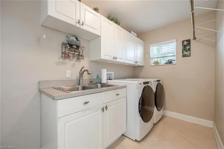 Laundry room with washer, dryer, cabinetry & a sink