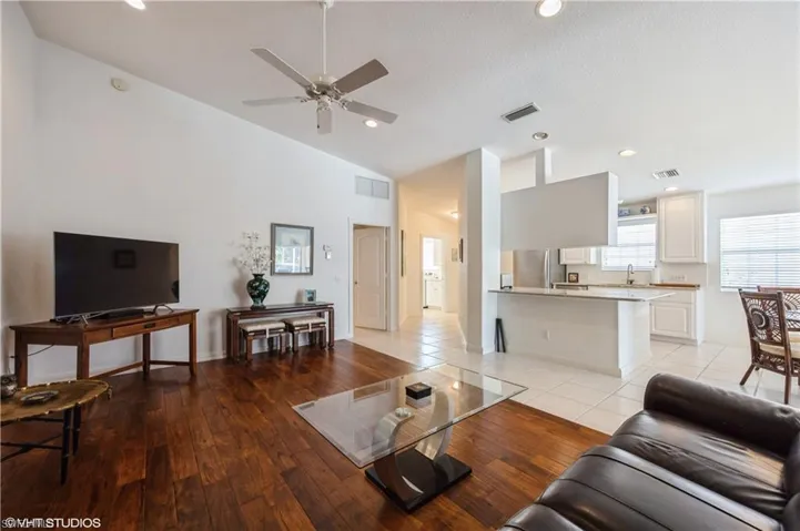 Living room featuring visible vents, vaulted ceiling, and ceiling fan