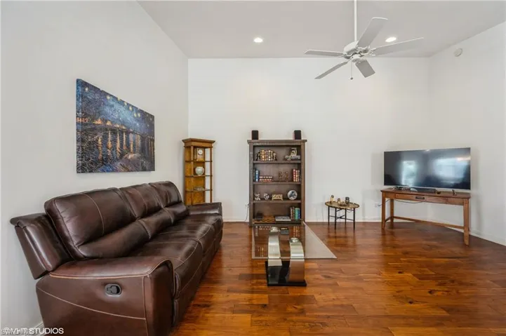 Living room with ceiling fan, a towering ceiling, recessed lighting, wood finished floors, and baseboards