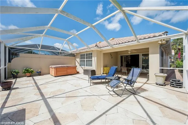 View of patio / terrace featuring ceiling fan, glass enclosure, and a hot tub