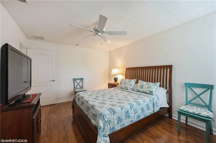 Bedroom featuring dark wood-type flooring, visible vents, baseboards, and a ceiling fan