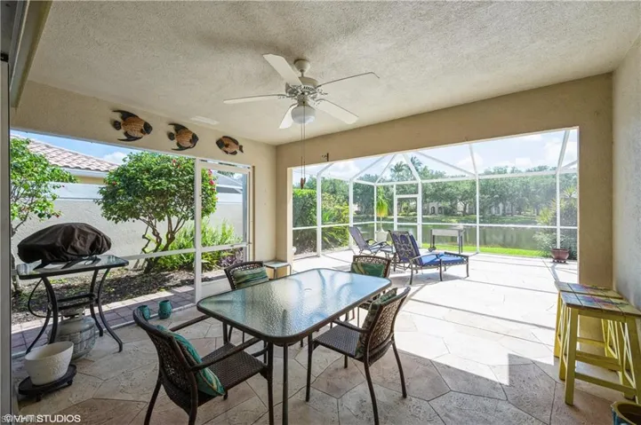 View of patio / terrace featuring a grill, outdoor dining area, a ceiling fan, and glass enclosure