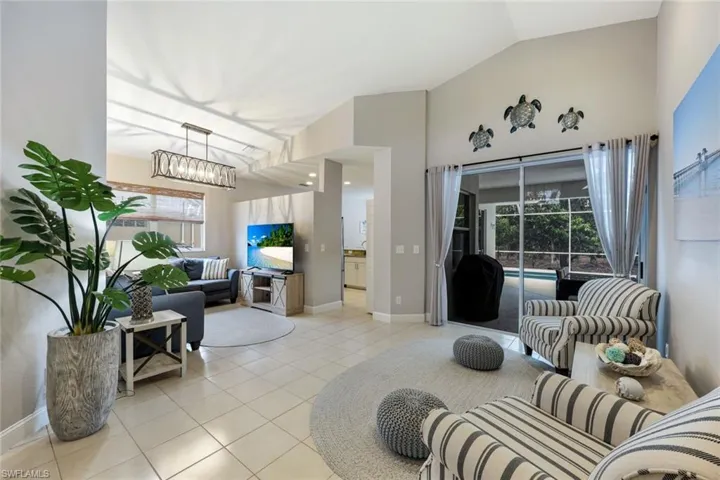 Living area with light tile patterned floors, lofted ceiling, plenty of natural light, and a chandelier