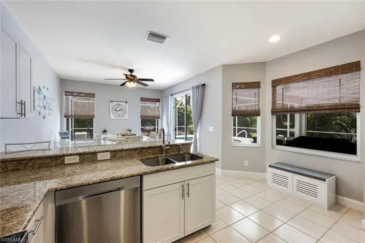 Kitchen featuring dishwasher, a ceiling fan, light tile patterned floors, stone counters, and recessed lighting