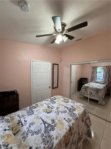 Tiled bedroom featuring ceiling fan and a closet