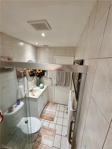 Bathroom featuring tile walls, tile patterned floors, vanity, and toilet