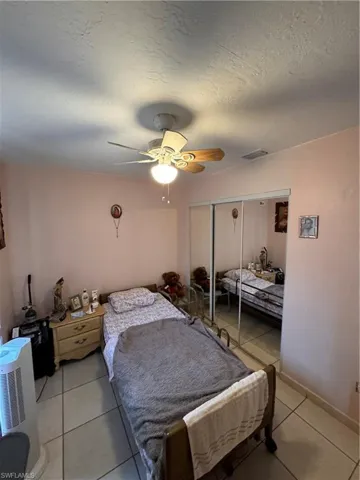 Tiled bedroom featuring ceiling fan and a closet